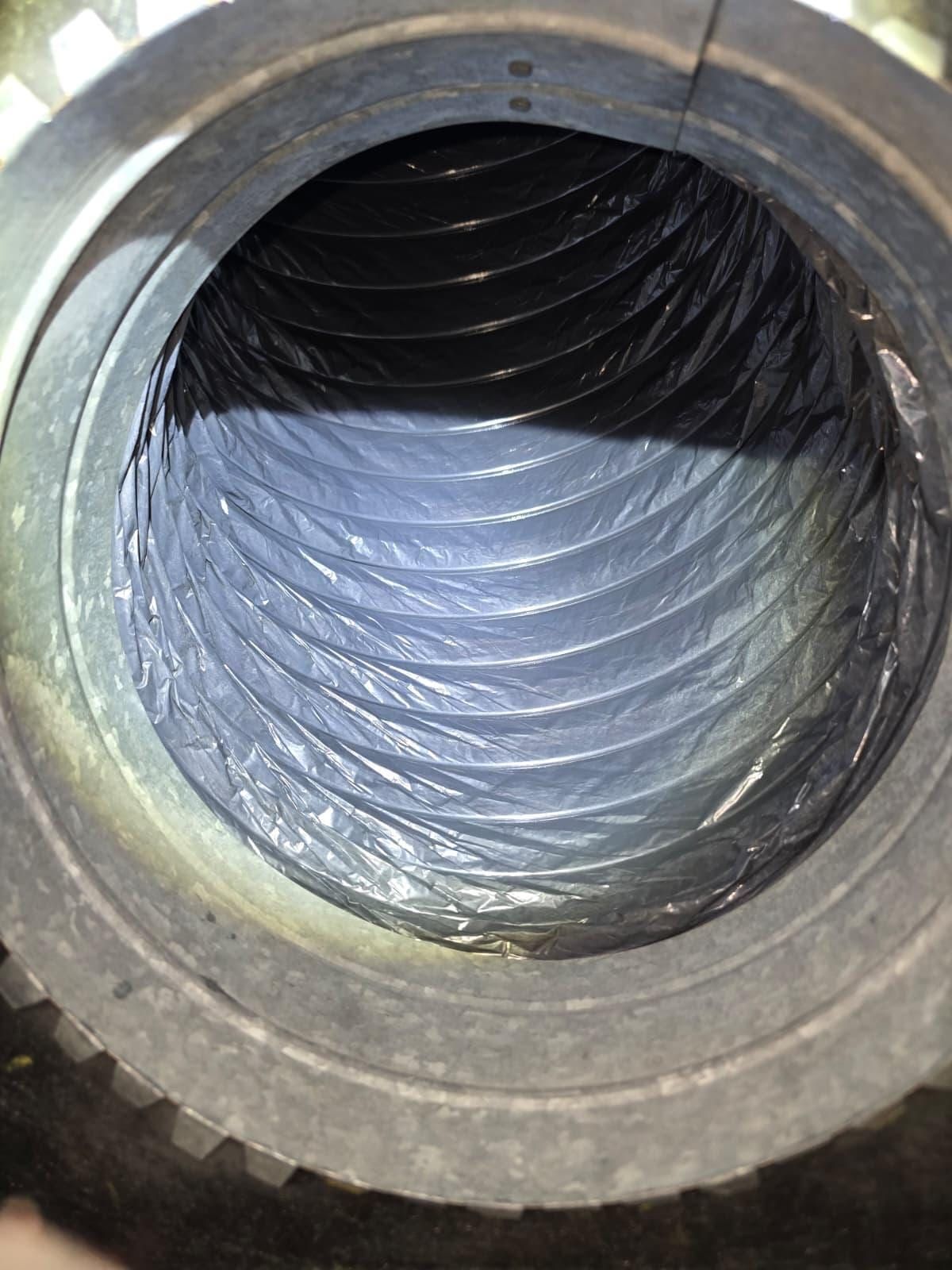 Interior de un ducto flexible visto a través de un collarín metálico, con relativamente poco polvo