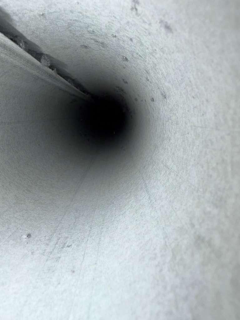 Interior de un ducto metálico limpio y brillante, visto a lo largo de un tramo en espiral
