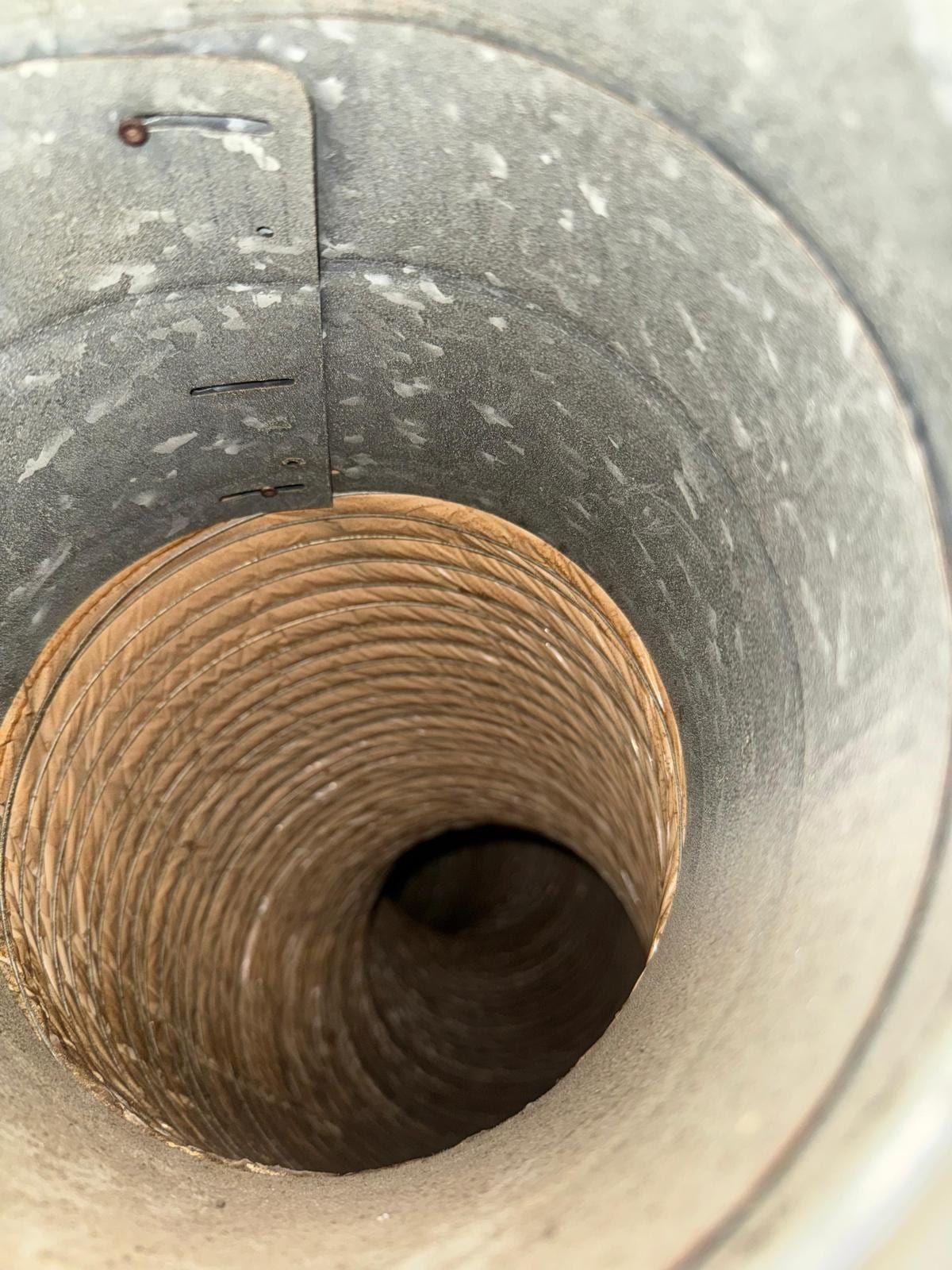 El interior de un ducto troncal galvanizado con la unión del collarín de un ducto flexible, con una ligera capa de polvo